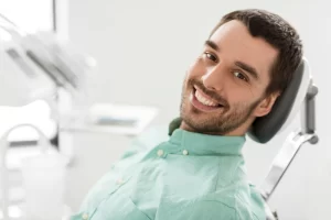 Happy male patient on dental chair after getting dental crown
